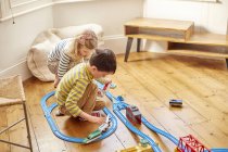 Молода дівчина і хлопчик грають з іграшковим набором поїздів — стокове фото
