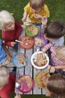 Vue aérienne de sept enfants mangeant des spaghettis à la table de pique-nique — Photo de stock
