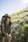 Madre llevando a su hija pequeña en la espalda, haciendo senderismo en el sendero de Bonneville Shoreline Trail en las colinas de Wasatch en Salt Lake City, Utah, EE.UU. - foto de stock