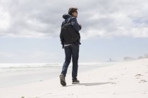 Rückansicht eines jungen Mannes, der allein am Strand spaziert, Westkap, Südafrika — Stockfoto