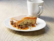 Plate of caramel cake with white mug on wooden table — Stock Photo