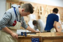 Maschio adolescente falegnameria studente regolazione morsetto di legno in laboratorio college — Foto stock