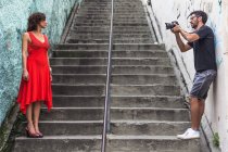 Detrás de las escenas de una sesión de moda urbana con modelo femenino y fotógrafo masculino - foto de stock