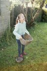 Дівчина тримає кошик у сільському саду — стокове фото