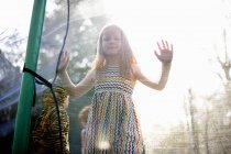Mädchen steht auf Trampolin im Garten — Stockfoto