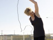Молода жінка обманює пропустивши мотузку під час тренування на парковці — стокове фото