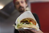 Young man serving hamburger from fast food van — Stock Photo