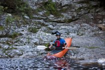 Mitte erwachsener Mann bewegt Kajak von Gewässerrand in Fluss — Stockfoto