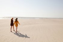 Мать и дочь гуляют по песчаному пляжу — стоковое фото