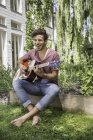 Молодий чоловік грає на гітарі в саду — стокове фото