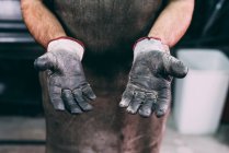 Mid section of metalworker protective gloves in forge workshop — Stock Photo