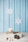 Chocolate cubes, hazelnuts, glass of milk, paper snowflakes on blue wall — Stock Photo