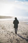 Vista trasera del hombre paseando por la playa ventosa, Sorso, Sassari, Cerdeña, Italia - foto de stock