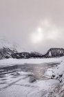 Frozen lake and snow covered mountains with cloudy sky — Stock Photo