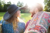 Вид сзади на романтическую молодую пару, несущую ковер для пикника в парке — стоковое фото