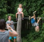 Mother photographing children playing on monkey bar — Stock Photo