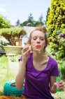 Frau pustet Blasen in Garten — Stockfoto