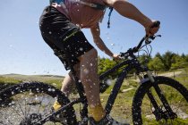 Side view of cyclists cycling through water — Stock Photo