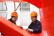 Trabajadores que miran la calidad del trabajo en las instalaciones de fabricación de grúas, China - foto de stock