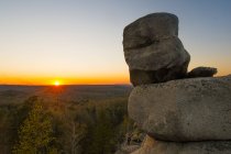 Boulders on cliff with sunset over horizon — Stock Photo