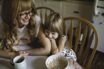 Mother and daughter cuddling at breakfast table — Stock Photo