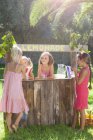 Four girls buying and selling at lemonade stand in park — Stock Photo