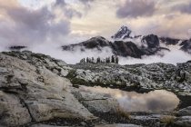 Тучи, окружающие скалистые горы на закате — стоковое фото