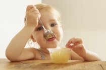 Retrato de uma criança comendo sobremesa à mesa — Fotografia de Stock