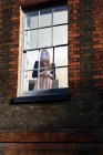 Donna in piedi vicino alla finestra con tazza — Foto stock
