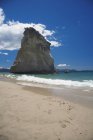 Formazione rocciosa sulla spiaggia sabbiosa con cielo azzurro vivo — Foto stock