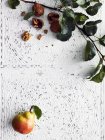 Грушевые фрукты и ветки рядом с грецкими орехами на декоративной поверхности — стоковое фото