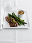 Plate of meat with asparagus and sauce — Stock Photo
