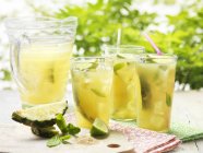Glasses of home made golden rum punch with lime, pineapple, mint and ice — Stock Photo