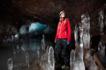 Турист со сталактитами в ледниковой пещере — стоковое фото