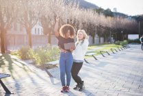 Zwei junge Freundinnen im park lachen über digitales tablet, como, italien — Stockfoto