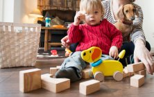 Garçon assis sur le sol avec des jouets en bois — Photo de stock