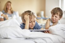 Ragazzi sul letto dei genitori con tablet digitale — Foto stock