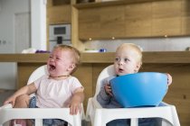 Male and female twins toddlers in high chairs — Stock Photo