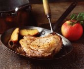 Pork chop sauteed with apple and onions in vintage frying pan — Stock Photo