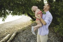 Mid adult man carrying and tickling daughter at Lake Ontario, Oshawa, Canada — Stock Photo