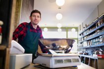 Grocer working behind counter at store — Stock Photo