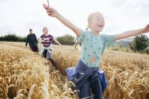 Menina correndo através do campo com os braços para fora — Fotografia de Stock