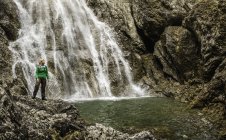 Jovem caminhante em pé em frente à cachoeira, Holzgau, Tirol, Áustria — Fotografia de Stock