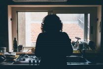 Rear silhouetted view of woman standing in front of kitchen sink — Stock Photo