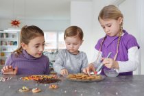 Girls at kitchen counter decorating cookies — Stock Photo