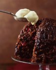 Christmas pudding with spoonful of cream, close up shot — Stock Photo