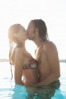 Casal romântico beijando na piscina ao ar livre — Fotografia de Stock