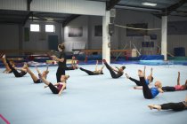 Інструктор з гімнастики наглядає за класом, що практикує розтяжки — стокове фото