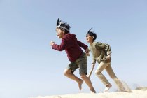 Two boys, wearing fancy dress, playing on sand — Stock Photo