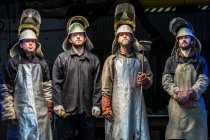 Portrait of four male foundry workers wearing protective clothing in bronze foundry — Stock Photo